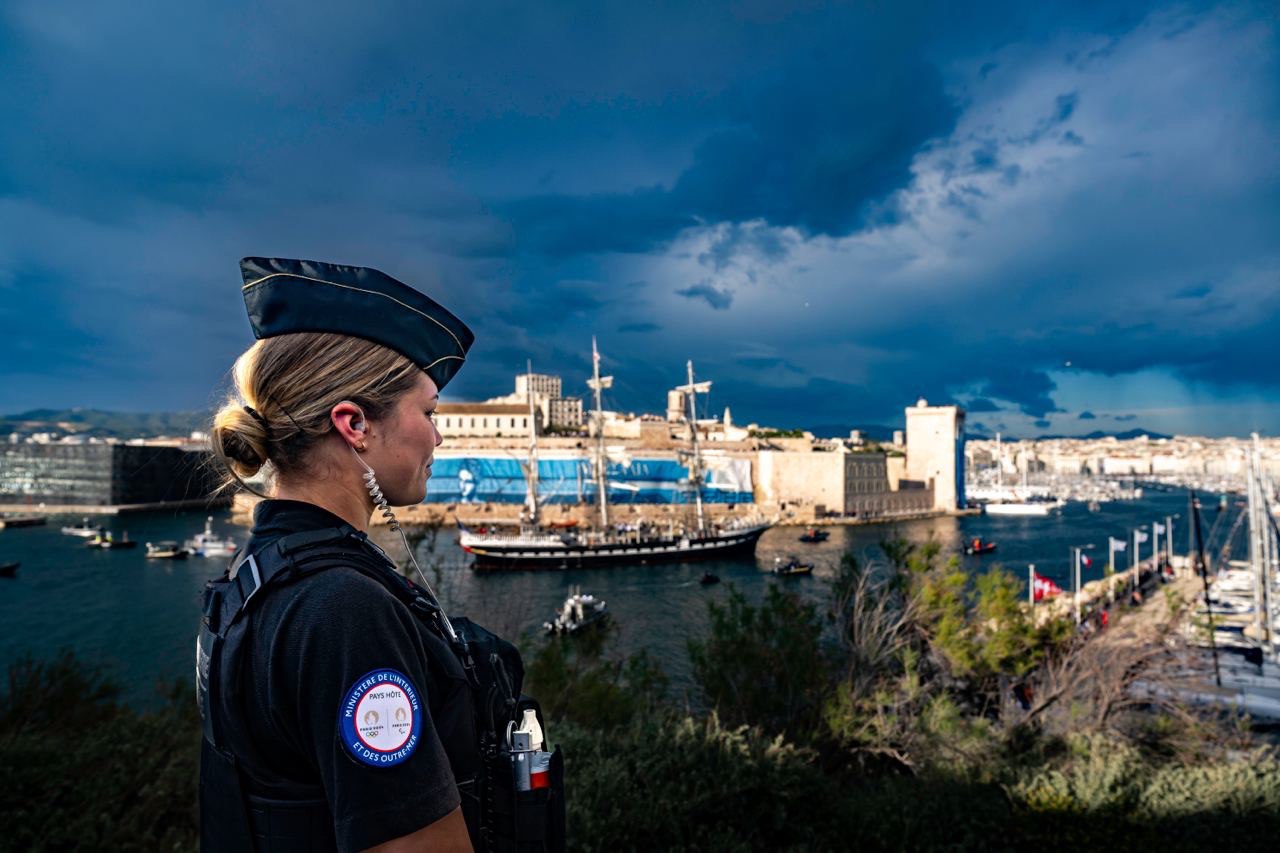 Une gendarme surveille l'arrivée du trois-mâts sur lequel se trouve la flamme olympique.