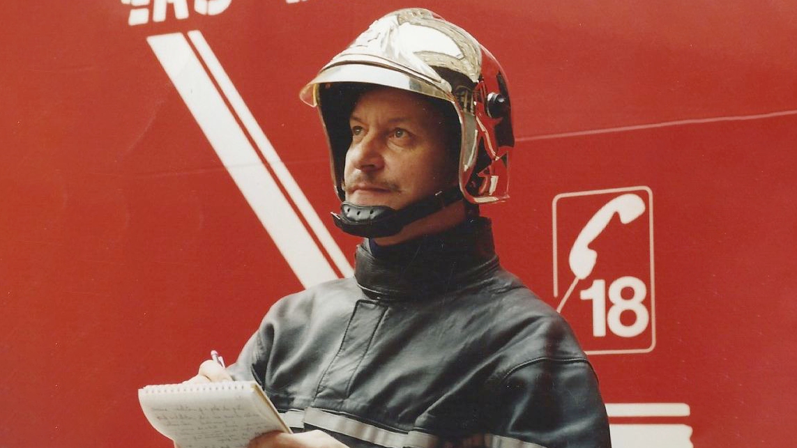 René Dosne en train de réaliser un croquis opérationnel. Il porte sa tenue de sapeur-pompier.
