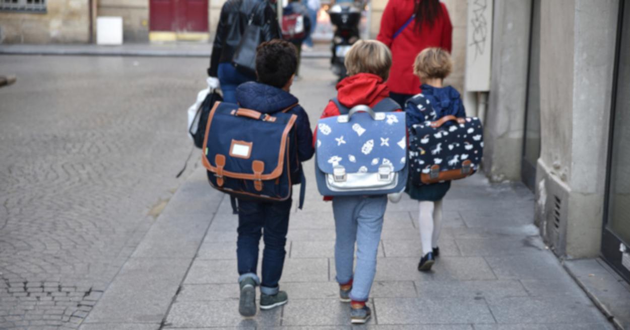 Enfants sur le chemin de l'école avec un cartable dns le dos